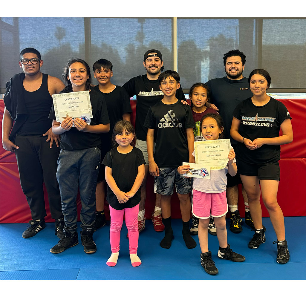 Cassandra Samel in wrestling gear posing on the mat at Adrenaline MMA & Fitness, showcasing her skills as a top young wrestler in San Bernardino.